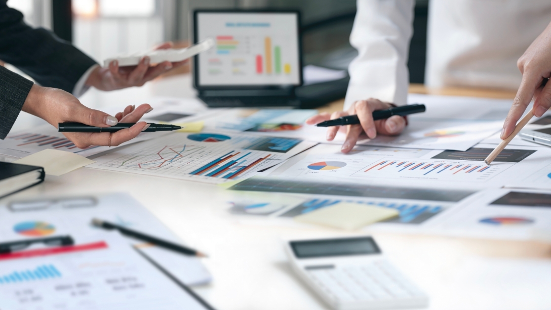 机の上に資料を広げてミーティングを行っているイメージ