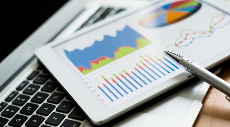 ノートパソコンの上にグラフが表示されたタブレットの画像